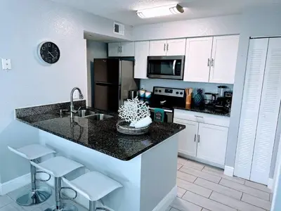 a kitchen with a sink and a counter with stools at Playing Hooky in Kissimmee