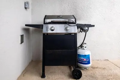 a gas grill with a water bottle next to it at Storeybook Escape - Sleeps 11 in Kissimmee