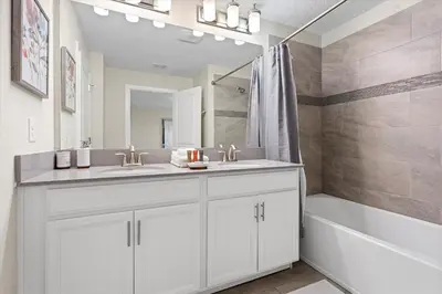a bathroom with two sinks and a tub and a mirror at 4 Bedrooms - 3 Bathrooms - Storey Lake 4818Ml in Kissimmee