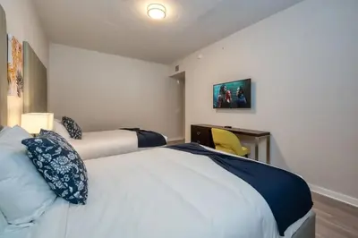 a bedroom with two beds and a yellow chair at Conforto e Estilo | 3Q Piscina & Resort in Orlando