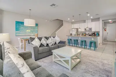 a living room with a couch and a table and a kitchen at 4 Mi to WDW Sleek Townhome with Community Pool! in Kissimmee