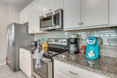 a kitchen with white cabinets and a stainless steel refrigerator at 4 Mi to WDW Sleek Townhome with Community Pool! in Kissimmee