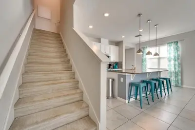 a staircase in a home with blue stools at 4 Mi to WDW Sleek Townhome with Community Pool! in Kissimmee