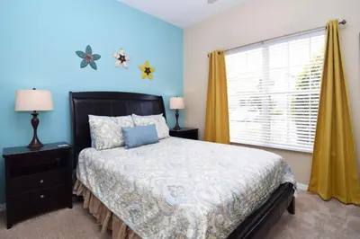 a bedroom with a bed with blue walls and a window at Fully Equipped Comfortable Townhouse in Kissimmee