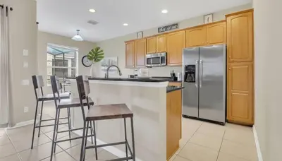 a kitchen with a stainless steel refrigerator and bar stools at Disney Retreat w/ Wizard & Galaxy Rooms in Orlando