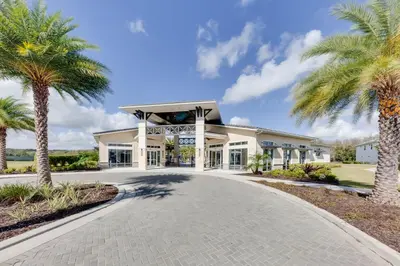 a building with palm trees in front of a road at Magical 15-Bedroom Villa | Game Room, Theater & More! in Kissimmee