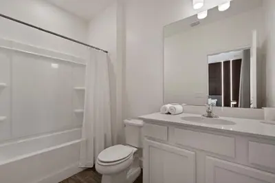 a white bathroom with a toilet and a sink at Magical 15-Bedroom Villa | Game Room, Theater & More! in Kissimmee