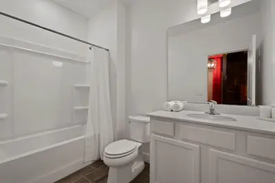 a white bathroom with a toilet and a sink at Magical 15-Bedroom Villa | Game Room, Theater & More! in Kissimmee