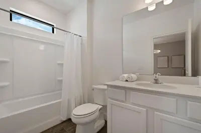 a white bathroom with a toilet and a sink at Magical 15-Bedroom Villa | Game Room, Theater & More! in Kissimmee