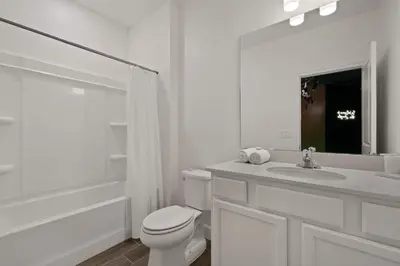 a white bathroom with a toilet and a sink at Magical 15-Bedroom Villa | Game Room, Theater & More! in Kissimmee