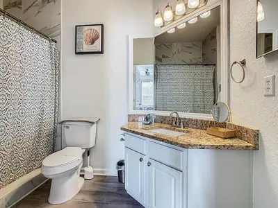 a bathroom with a toilet and a sink and a mirror at Windsor Hills Modern 3BR Condo with Resort Amenities in Orlando