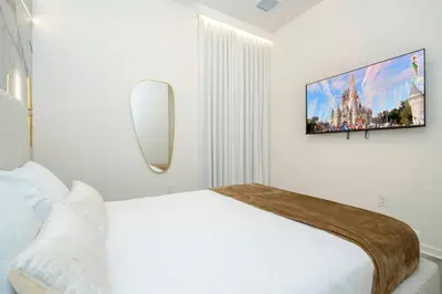 a white bedroom with a bed and a flat screen tv at Paradiso Grande 5 Bed New Townhome - 10329 in Orlando