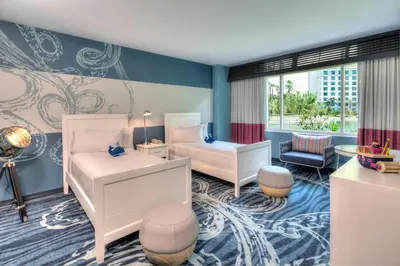 a childrens bedroom with two beds and a chair at Universal's Loews Sapphire Falls Resort in Orlando