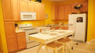 a kitchen with a table and a white refrigerator at SHVCK1 - Coral Cay Resort #1 - 4 Bedroom Townhouse in Kissimmee