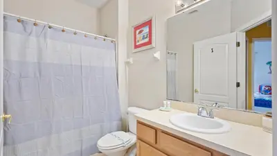 a bathroom with a sink and a toilet and a mirror at SHVCK3 - Coral Cay Resort #3 - 4 Bed 3 Baths Townhome in Kissimmee