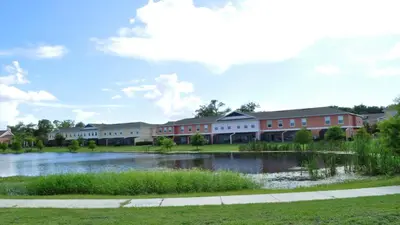 a building with a lake in front of it at SHVCK5 - Coral Cay Resort #5 - 4 Bed 3 Baths Townhome in Kissimmee