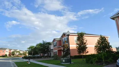 a building on a street with trees in front of it at SHVCK5 - Coral Cay Resort #5 - 4 Bed 3 Baths Townhome in Kissimmee