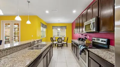 a kitchen with yellow and red walls and counters at SHVCC1 - Crystal Cove #1 - 7 Bed 4.5 Baths Villa in Kissimmee