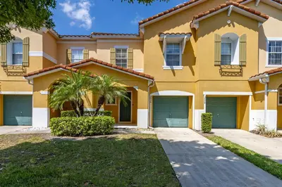 a large yellow house with two garage doors at Spacious Lakefront Townhouse 10 Mins To Disney in Kissimmee