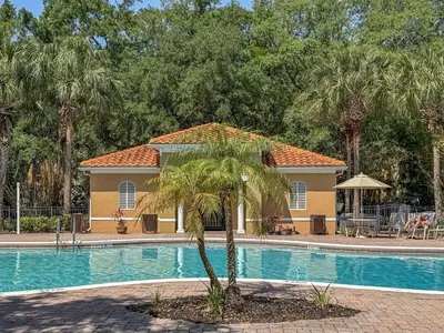 a house with a palm tree next to a swimming pool at Spacious Lakefront Townhouse 10 Mins To Disney in Kissimmee