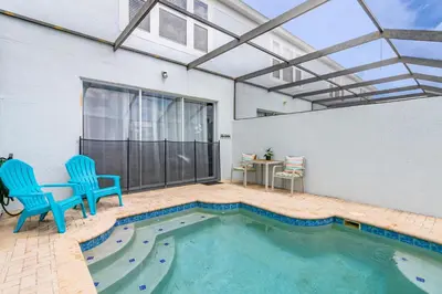 a swimming pool with two blue chairs and a table at Cozy 3Br Villa With Pool Disney Nearby in Orlando