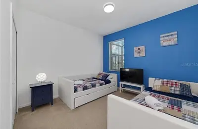 a living room with two beds and a blue wall at Luxury Family Villa With Pool & Bbq Near Disney! in Kissimmee