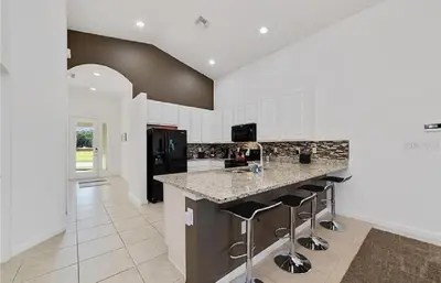 a kitchen with a counter and bar stools at Luxury Family Villa With Pool & Bbq Near Disney! in Kissimmee