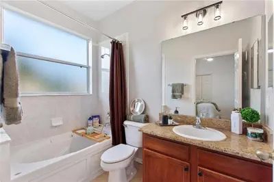 a bathroom with a tub and a toilet and a sink at 4Br Pool Villa, Near Disney - Gated Resort! in Kissimmee
