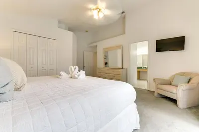 a white bedroom with a large white bed and a chair at 4 Mi to Disney Home with Pool Table, Outdoor Oasis! in Orlando