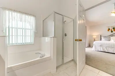 a white bathroom with a shower and a bed at 4 Mi to Disney Home with Pool Table, Outdoor Oasis! in Orlando
