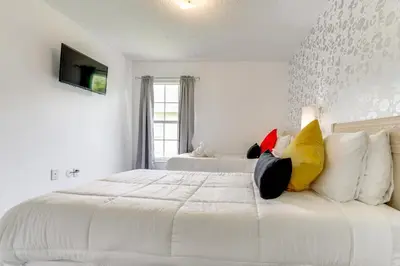 a white bedroom with a large white bed with pillows at 4 Mi to Disney Home with Pool Table, Outdoor Oasis! in Orlando