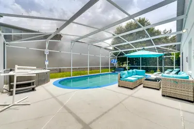 a swimming pool with a retractable roof with chairs and a table at 4 Mi to Disney Home with Pool Table, Outdoor Oasis! in Orlando