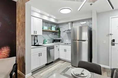a kitchen with white cabinets and a stainless steel refrigerator at 1 BR1 Bath sleeps 6 Close to Universal Parks in Orlando