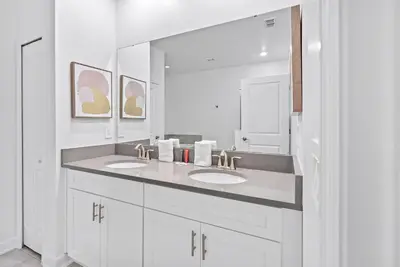 a white bathroom with two sinks and a mirror at NEW Home 09 BedroomsPoolGame Room in Kissimmee