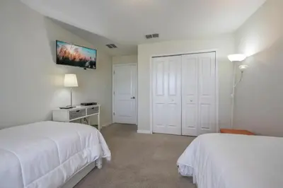 a bedroom with two beds and a tv on the wall at Casa 4 Quartos c/ Piscina – 10 Min da Disney in Kissimmee