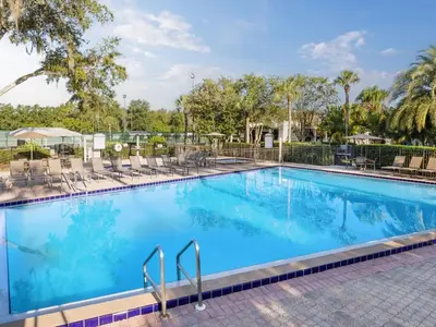 a large blue swimming pool with chairs and trees at Sheraton Vistana Resort One Bedroom Apartment in Orlando