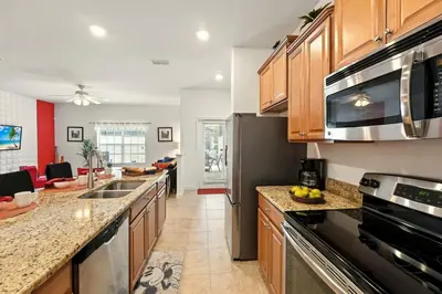 a kitchen with wooden cabinets and stainless steel appliances at Vibrant 5BR Family Retreat in Storey Lake in Kissimmee