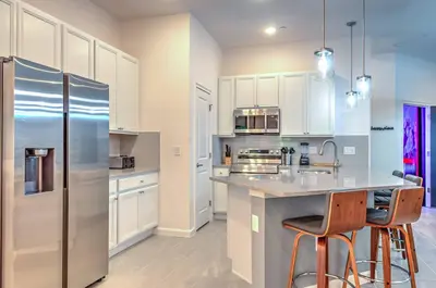 a kitchen with white cabinets and a stainless steel refrigerator at 10461 Amazing 5BD Family Townhouse at Paradiso Grande in Orlando