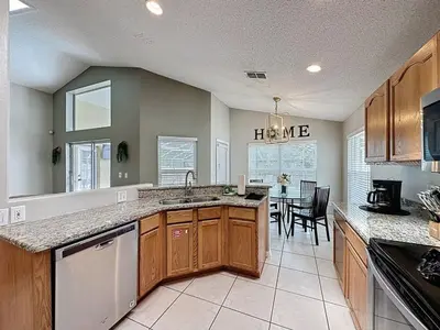 a kitchen with wooden cabinets and a dining room at Casa del Sol at Indian Creek Four Corners villa in Kissimmee
