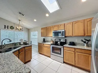 a kitchen with wooden cabinets and a stove top oven at Casa del Sol at Indian Creek Four Corners villa in Kissimmee