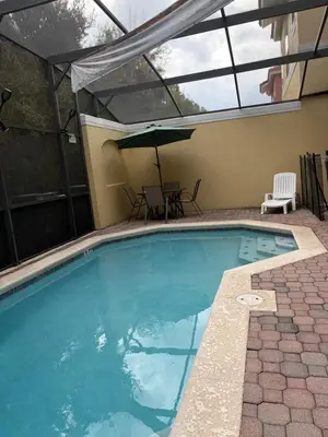 a swimming pool with a table and an umbrella at Disney Universal Theme Home! Private Pool! in Kissimmee