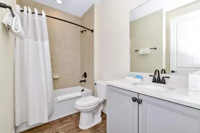 a white bathroom with a toilet and a sink at Paradise Breeze Cottage by Shine Villas - Margaritaville Resort Orlando condo in Orlando