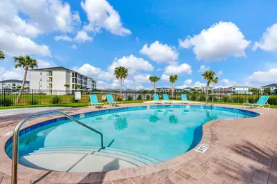 a large swimming pool with chairs and palm trees at Paradise Breeze Cottage by Shine Villas - Margaritaville Resort Orlando condo in Orlando