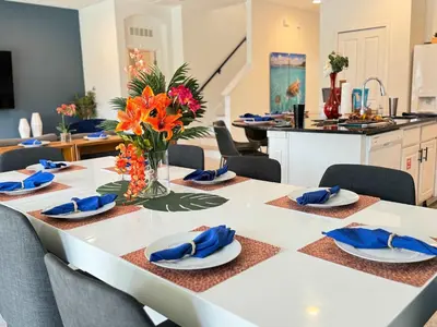 a dining room with a white table with blue napkins at Enchanted Escape-Perfect Pool to Relax & Recharge in Kissimmee