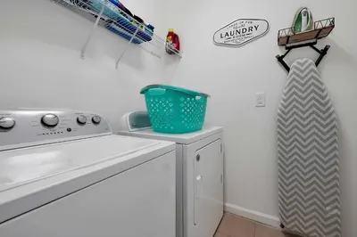 a laundry room with a washing machine and a basket at Enchanted Escape-Perfect Pool to Relax & Recharge in Kissimmee