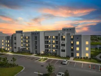 an apartment building with a parking lot at sunset at 2 Bedrooms 2 Bathrooms Storey Lake 3151-404 in Kissimmee