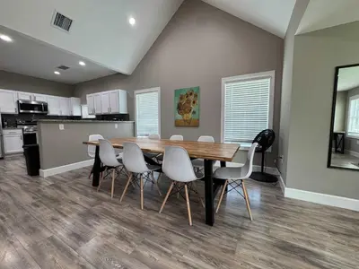 a dining room with a wooden table and white chairs at Peace in the Garden - Home in Winter Garden in Orlando