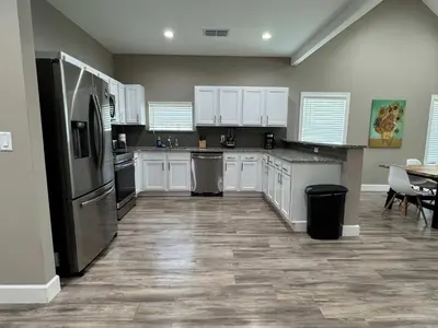 a kitchen with white cabinets and stainless steel appliances at Peace in the Garden - Home in Winter Garden in Orlando