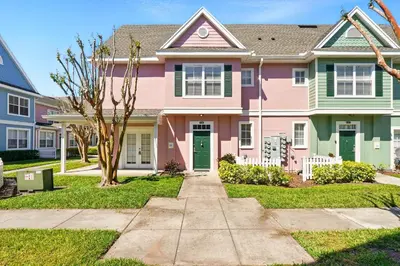 a pink house with green doors in a yard at Your Orlando Escape - Gated Resort with Amenities in Kissimmee
