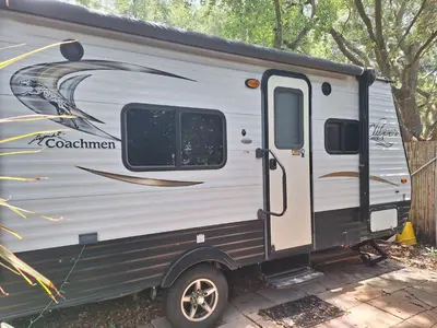 a silver and black trailer parked next to a fence at Tiny Trailer happy hole in the wall in Orlando